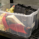 A black briefcase, along with various forgotten items, sits in a plastic bin.